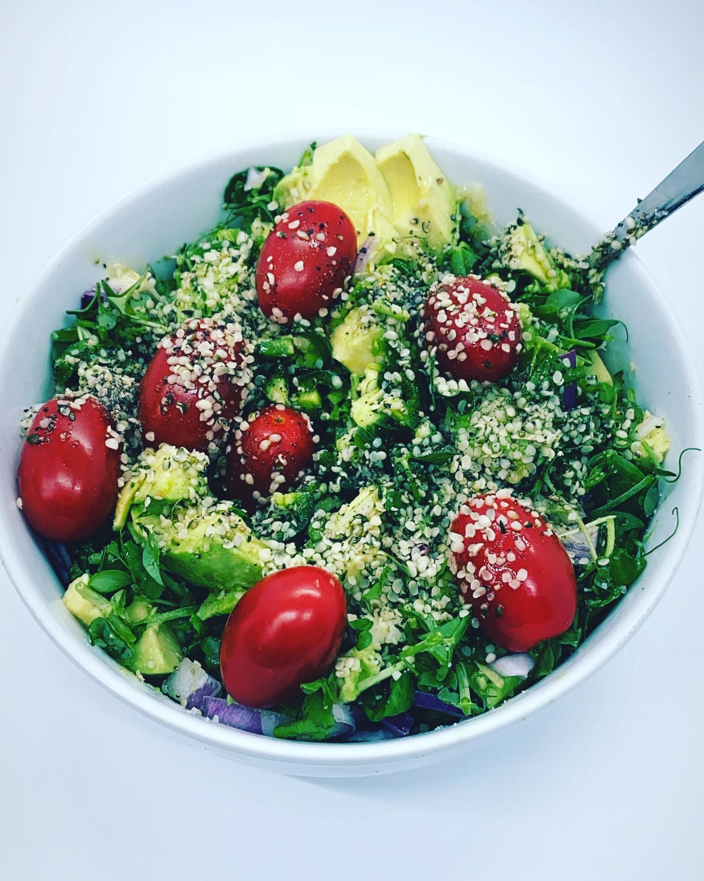 a bowl of salad with tomatoes avocado and sesame seeds