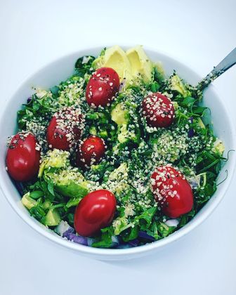 a bowl of salad with tomatoes avocado and sesame seeds
