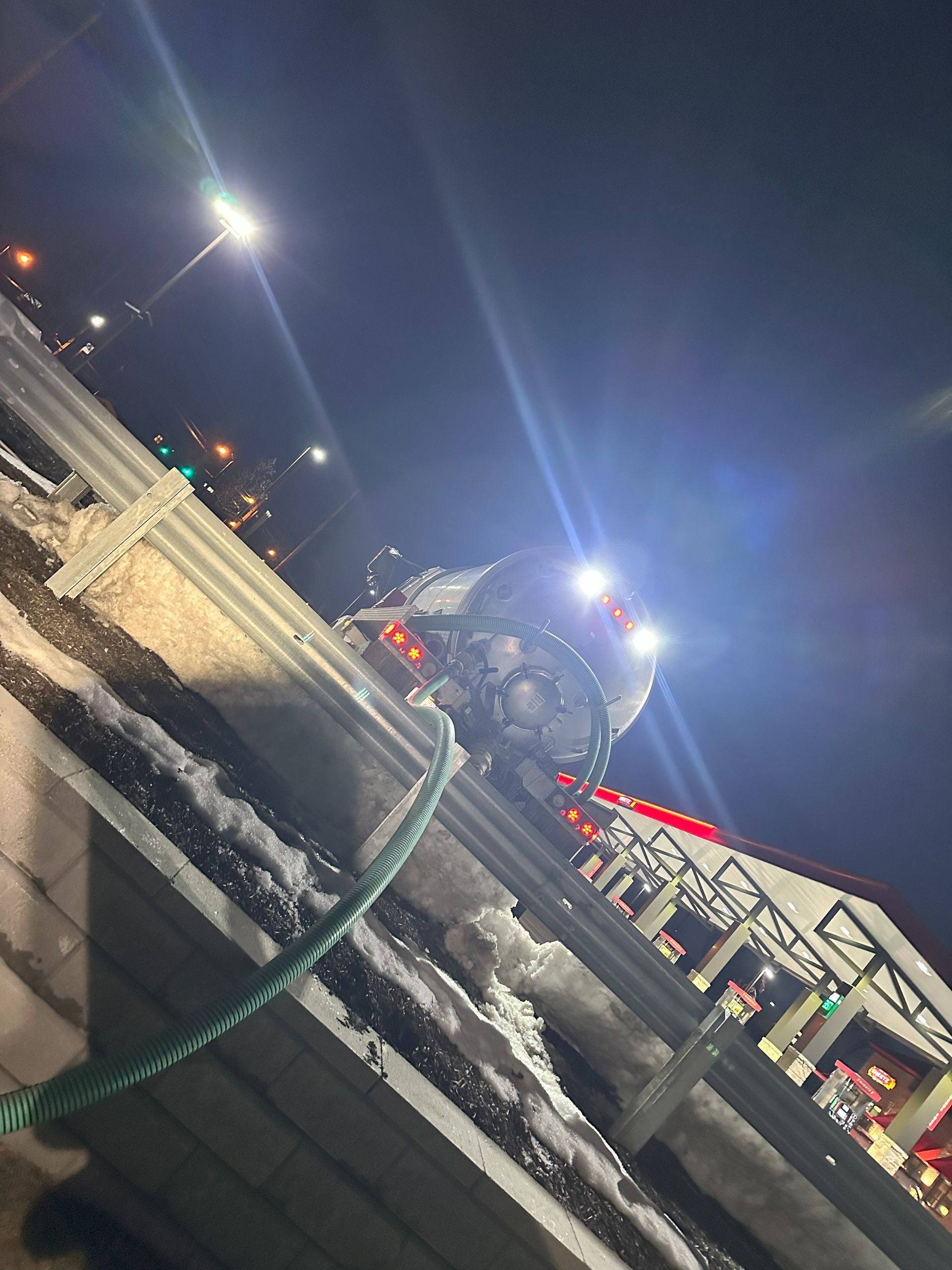 A truck with a hose attached to it is parked in front of a building at night.