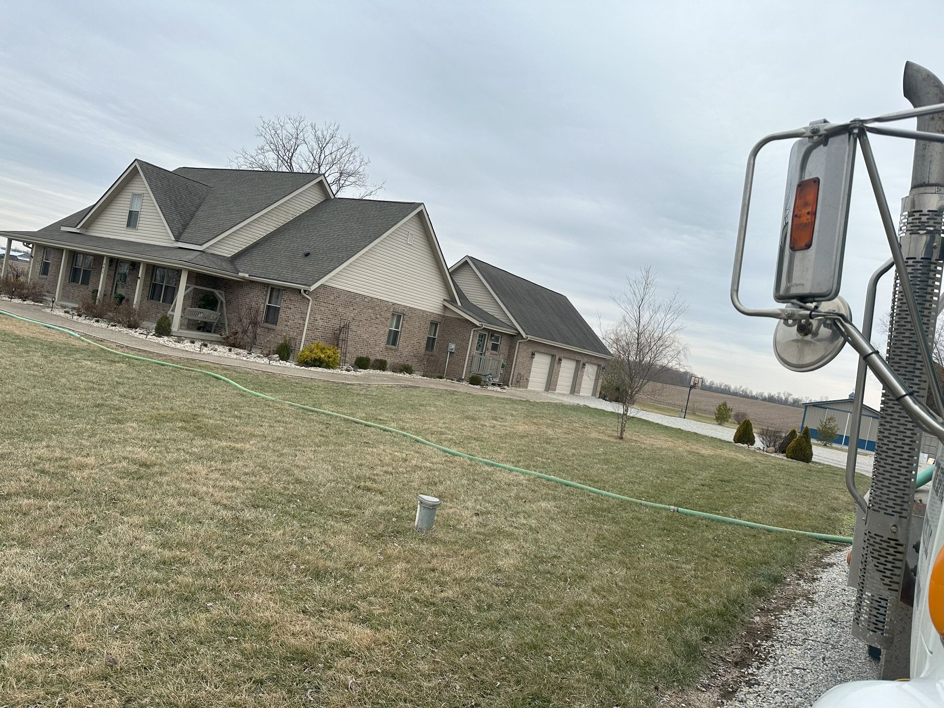 A large house is sitting on top of a grassy hill next to a truck.