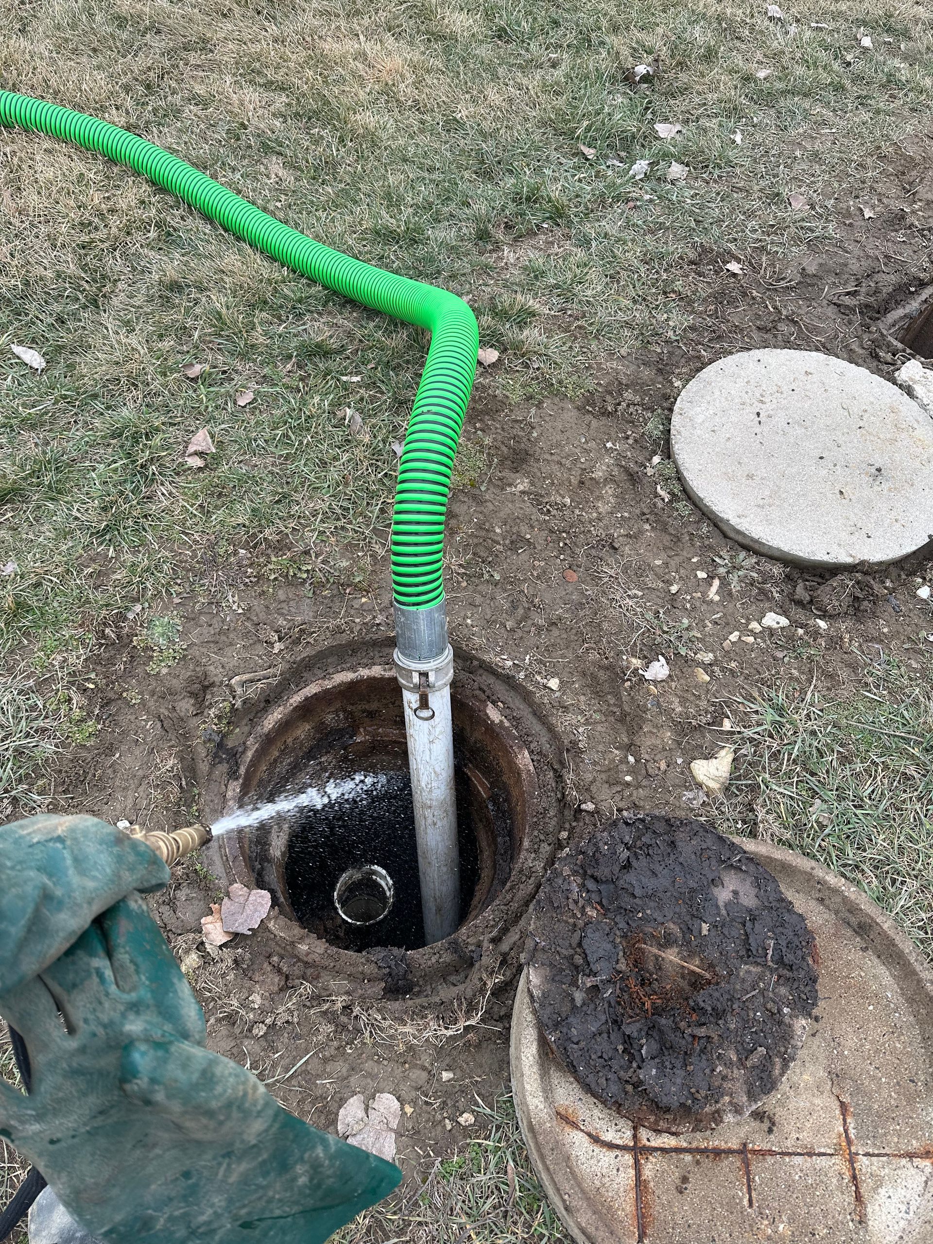 A green hose is connected to a septic tank.