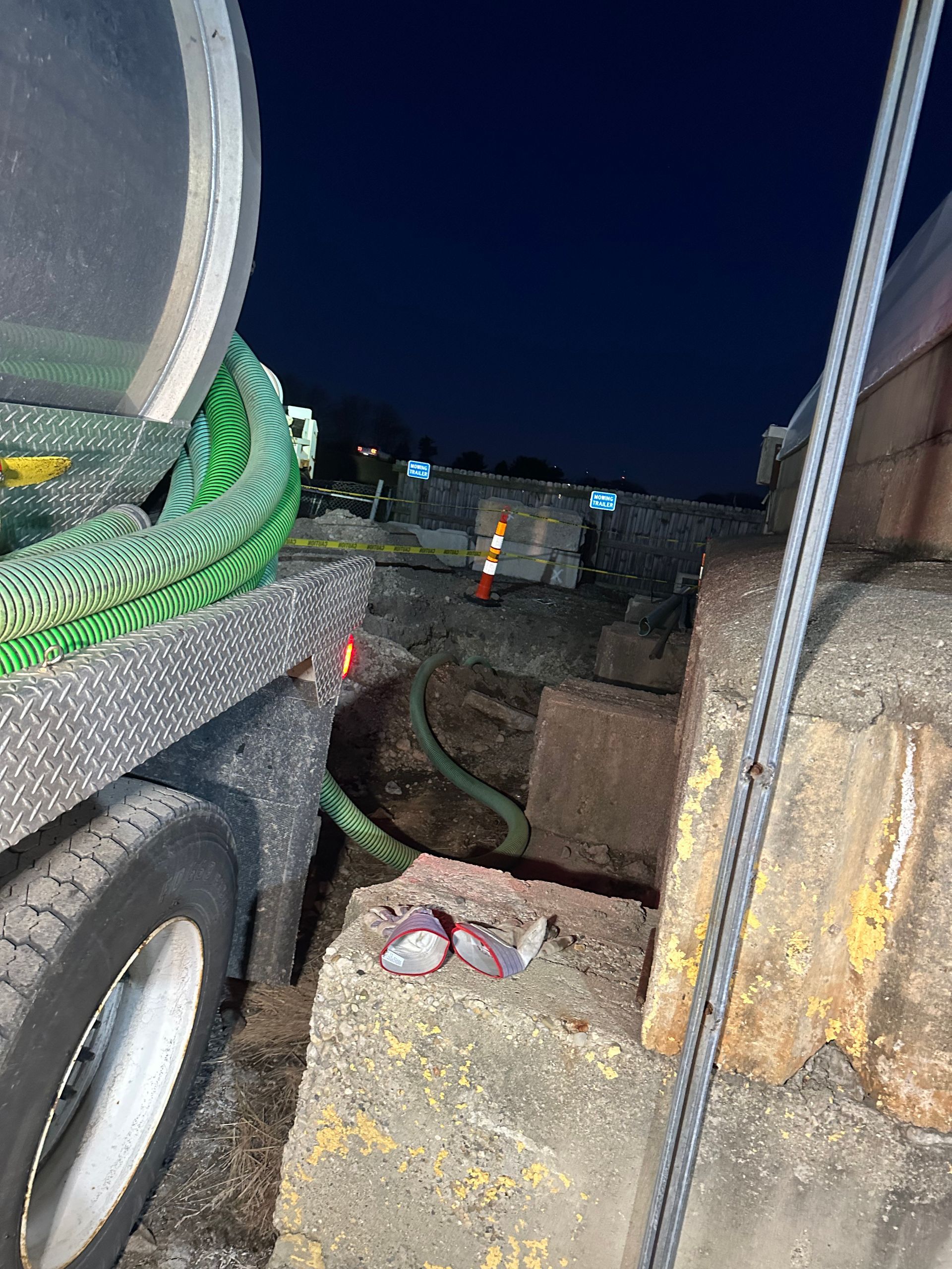A green hose is attached to the back of a truck.