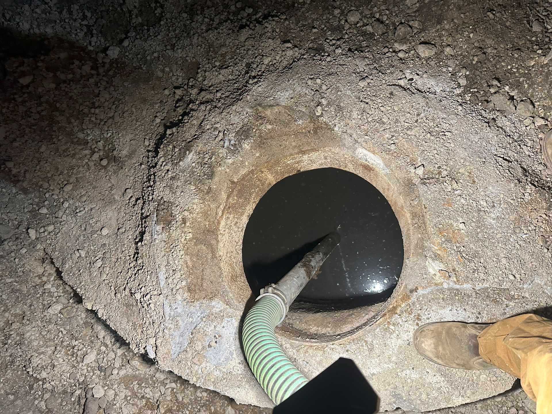 A person is hydro jetting into a hole in the ground.