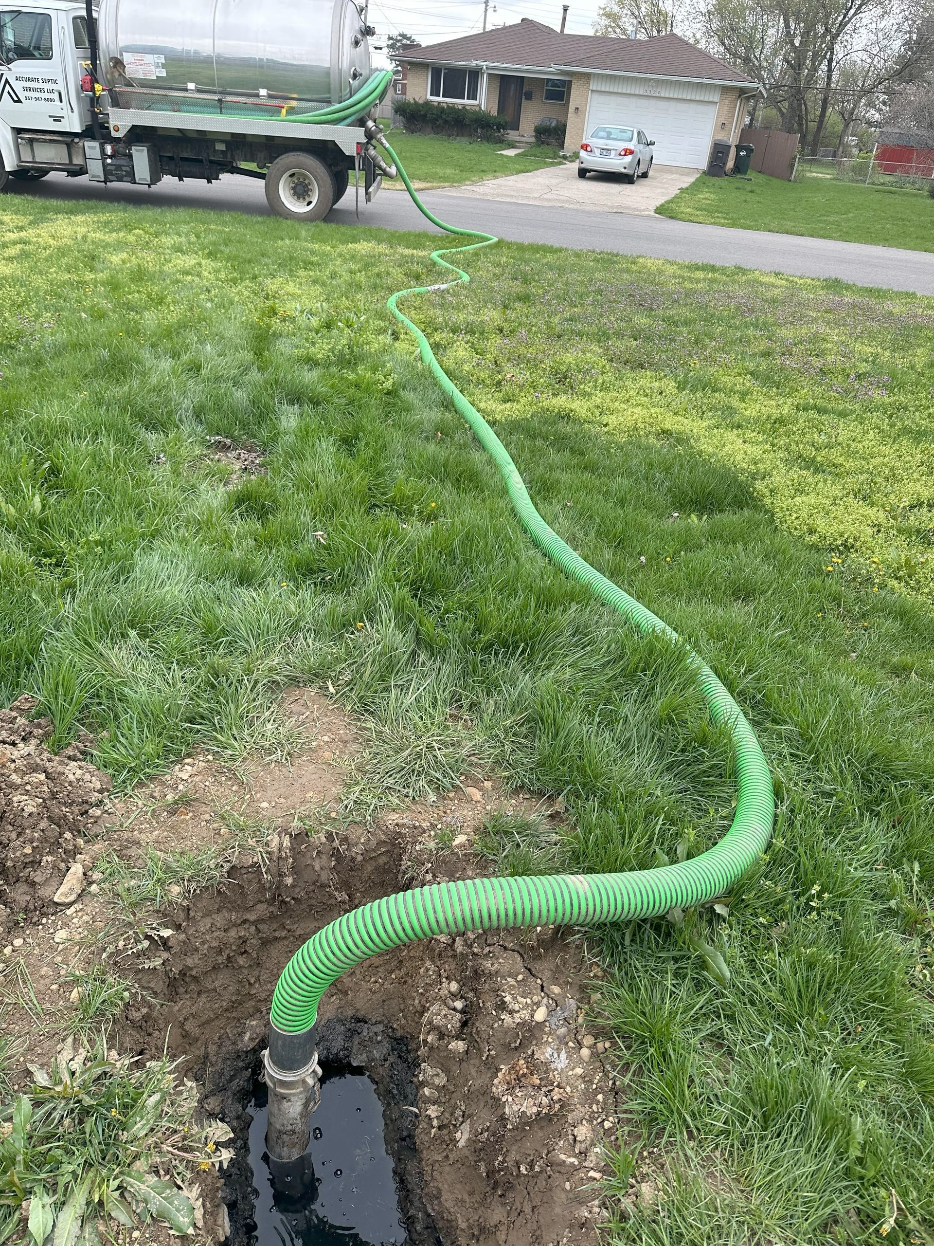 A septic truck is pumping water into a hole in the ground.