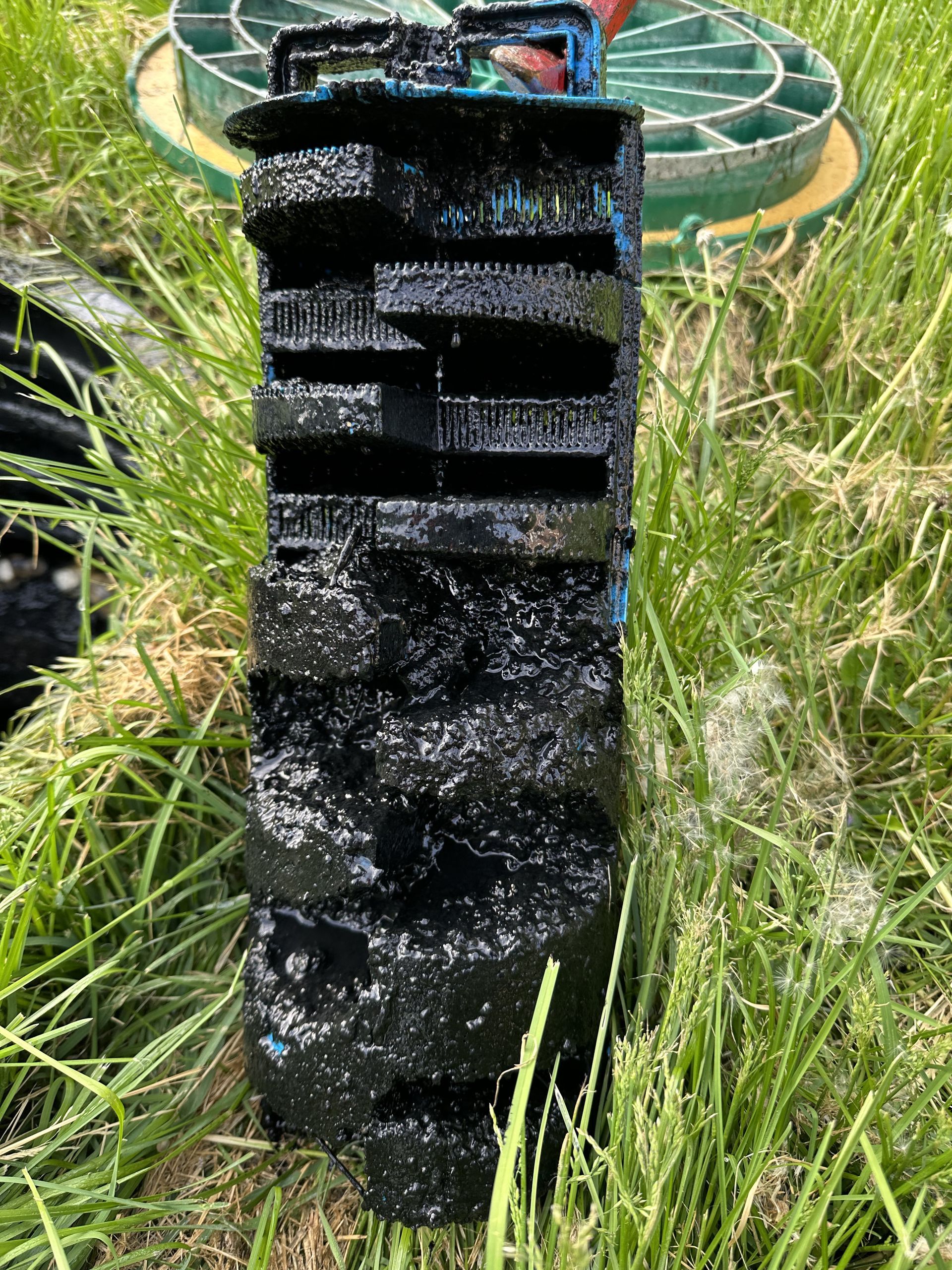 A tire is sitting in the grass next to a septic tank.