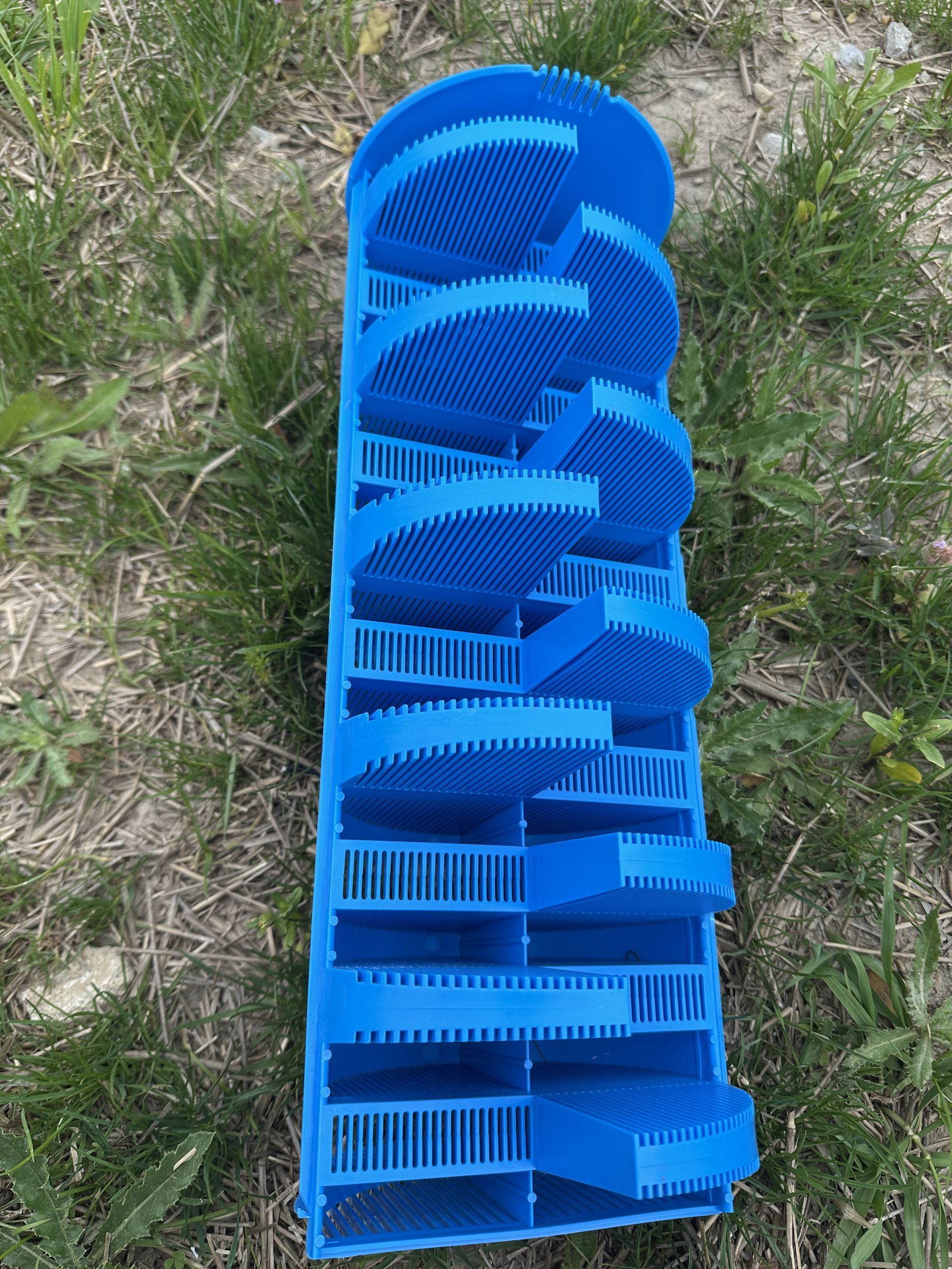 A blue brush holder is sitting on top of a lush green field.