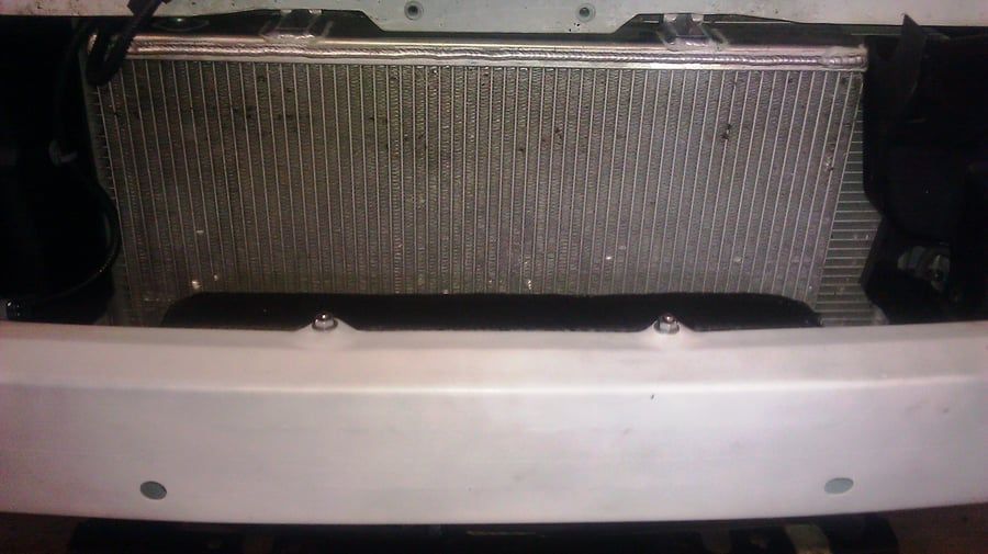 Close-up of a car grille with a silver front bumper in the foreground.