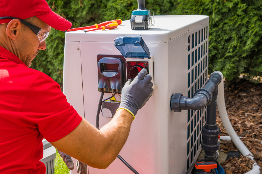 A man in a red shirt is working on a pool heater.