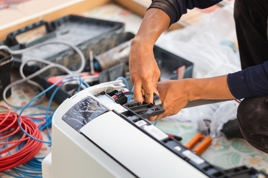 A man is fixing an air conditioner on the floor.