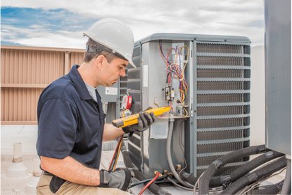 A man wearing a hard hat is working on an air conditioner.