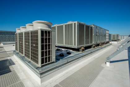 There are a lot of air conditioners on the roof of a building.