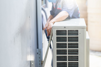 A man is installing an air conditioner on a wall.