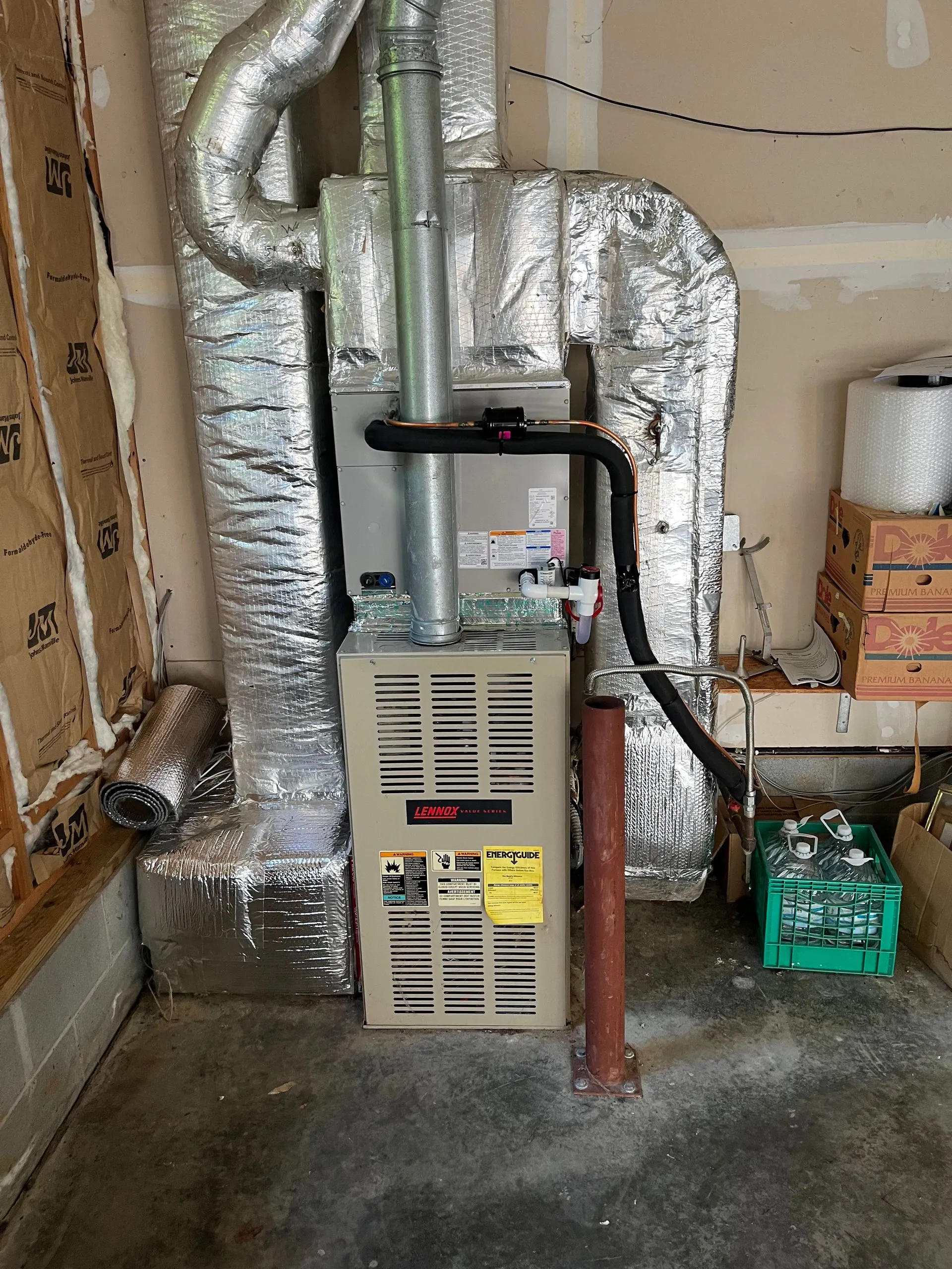 A furnace is sitting in a garage next to a wall.