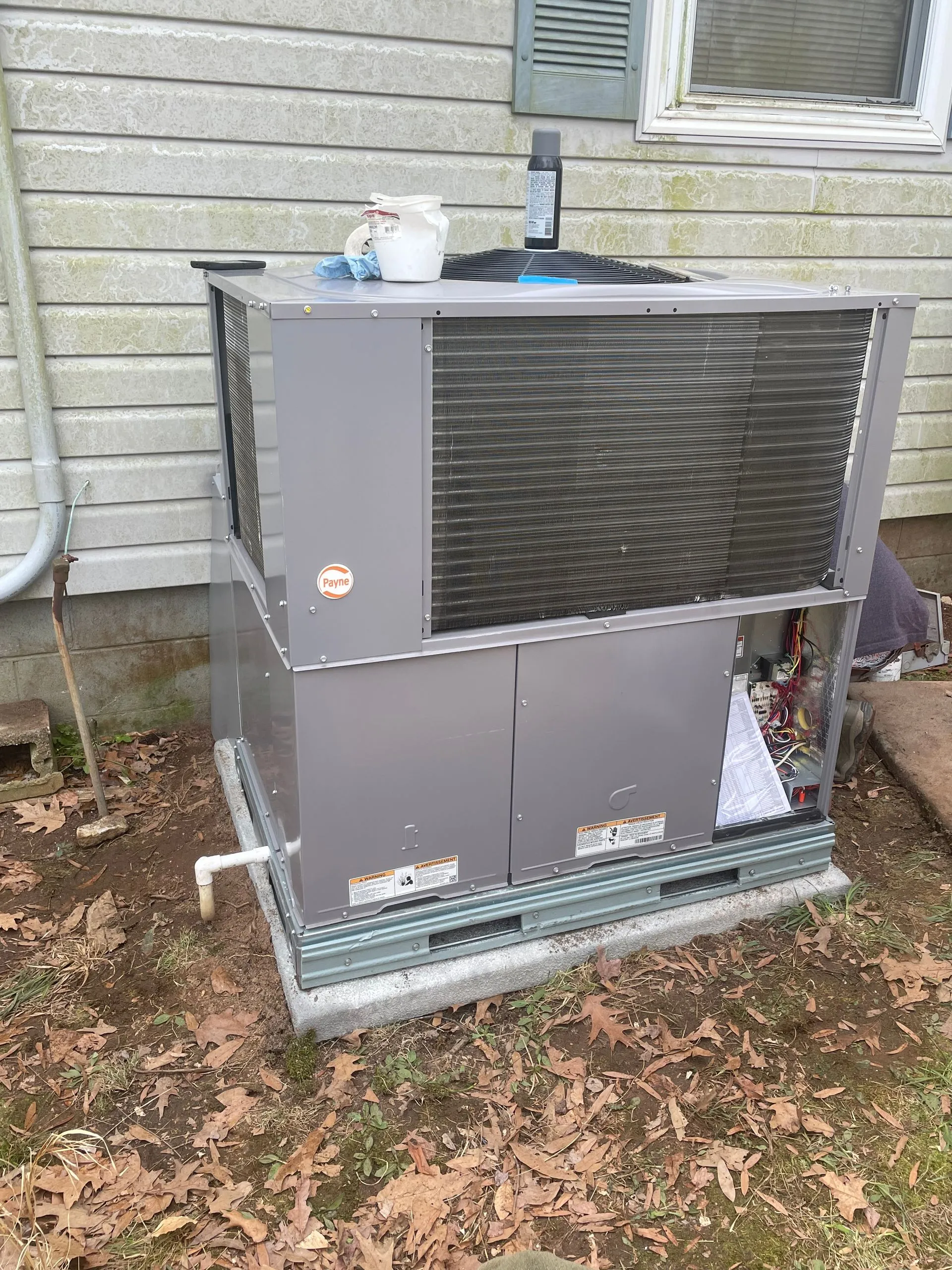 A large air conditioner is sitting outside of a house.