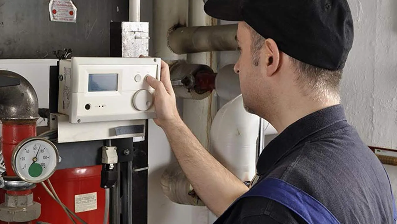 A man in a black hat is working on a heating system.