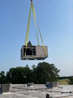 A crane is lifting an air conditioner into the air.
