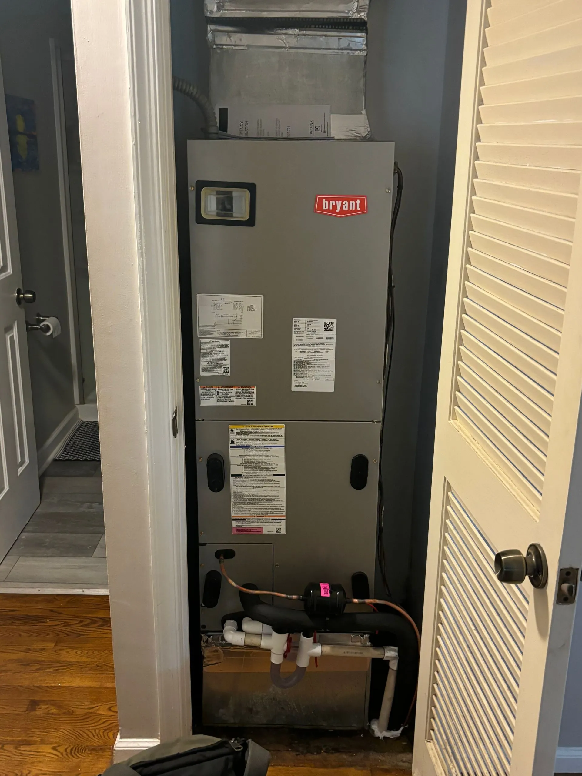 A furnace is sitting in a closet next to a door.
