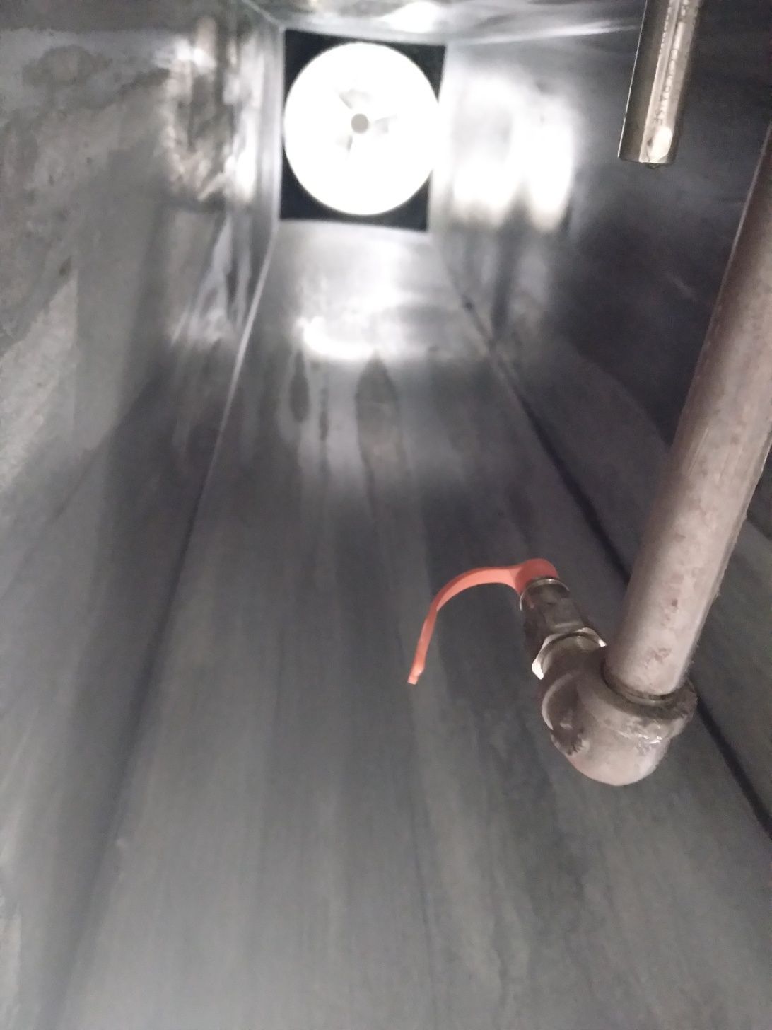 A stainless steel pipe is hanging from the ceiling of a building.