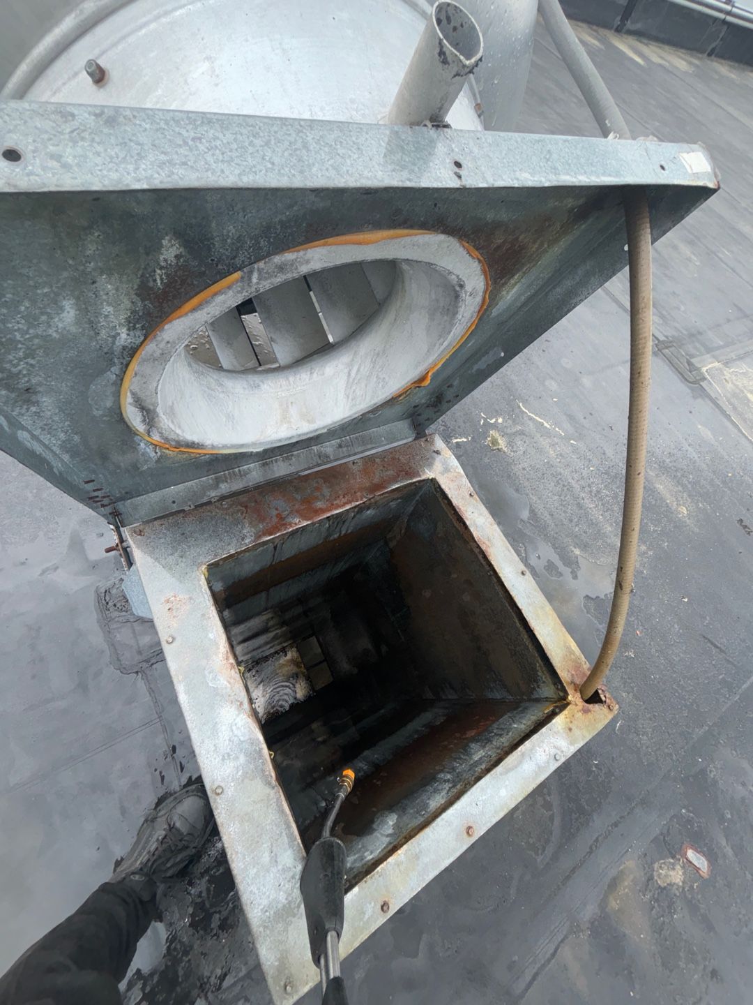A fan is sitting on top of a roof with the lid open.