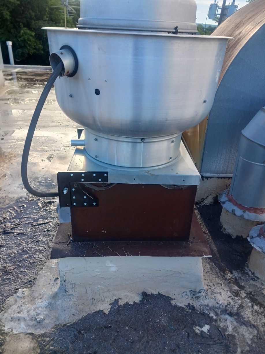 A large metal fan is sitting on top of a roof.