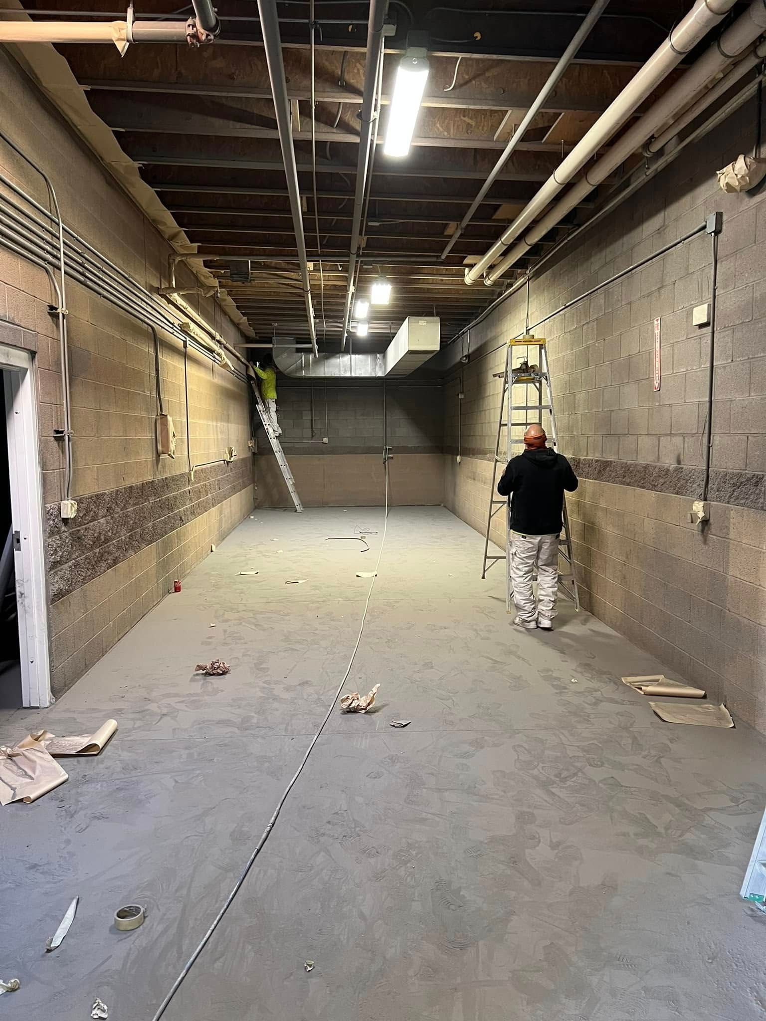 A man is standing in an empty room with a ladder.