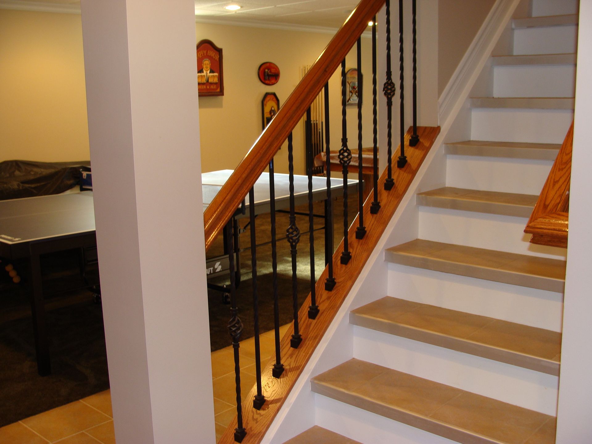 Staircase with wooden steps and railing, leading down. Wall and columns in view.