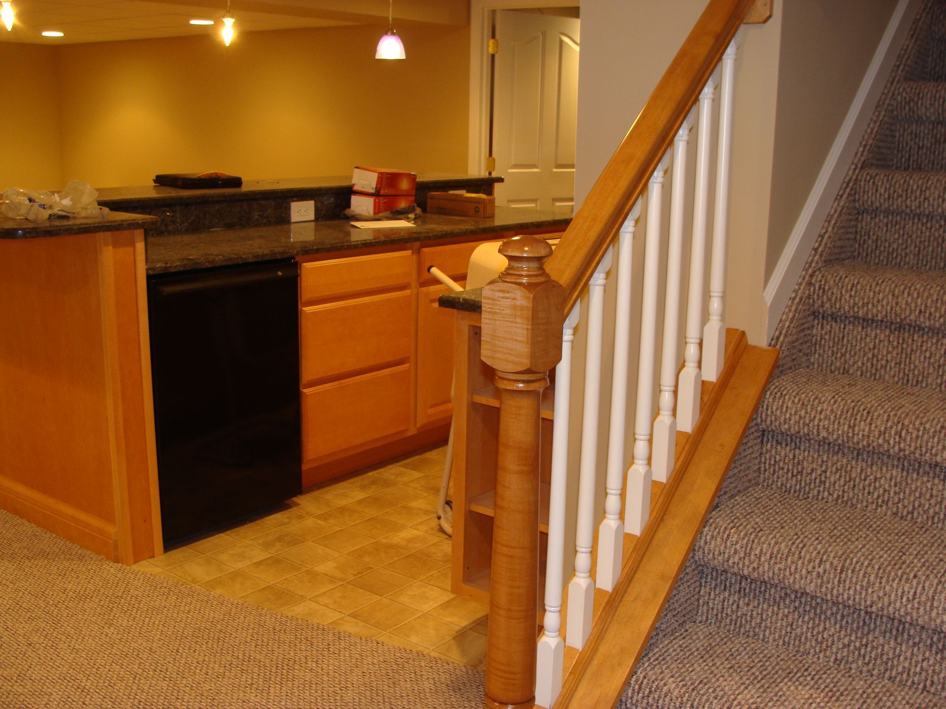 Interior view of a basement with a bar, cabinets, and stairs.
