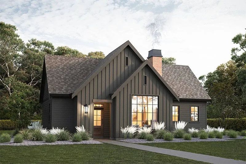 Dark-colored modern farmhouse with gabled roof, chimney, and large windows. Green lawn and trees surround the house.