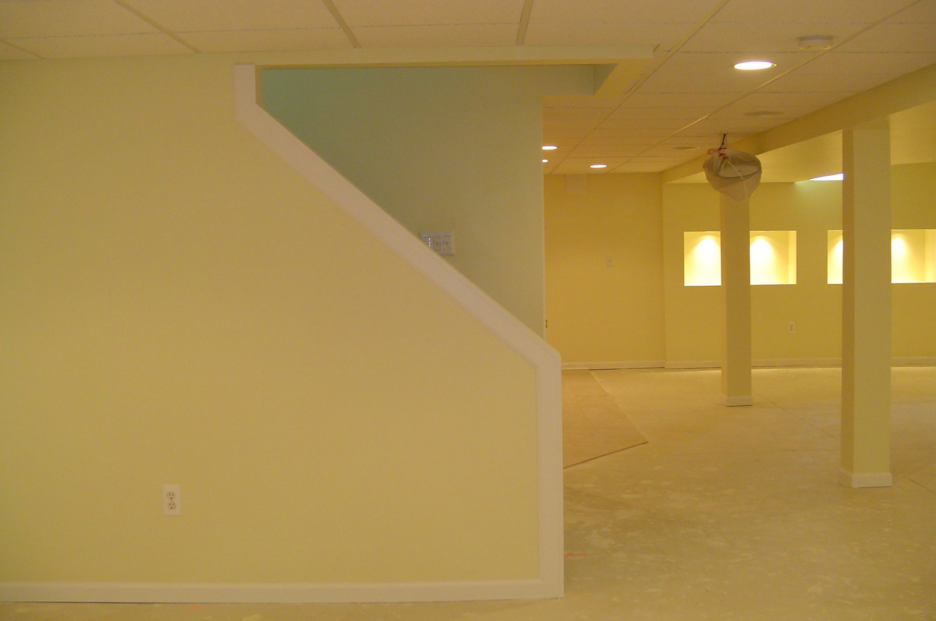 Yellow-painted basement with stairs, support columns, and recessed niches.