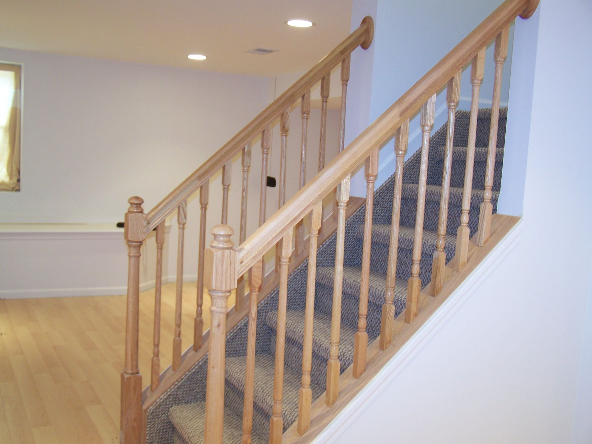 Wooden staircase with carpeted steps and light-colored walls.