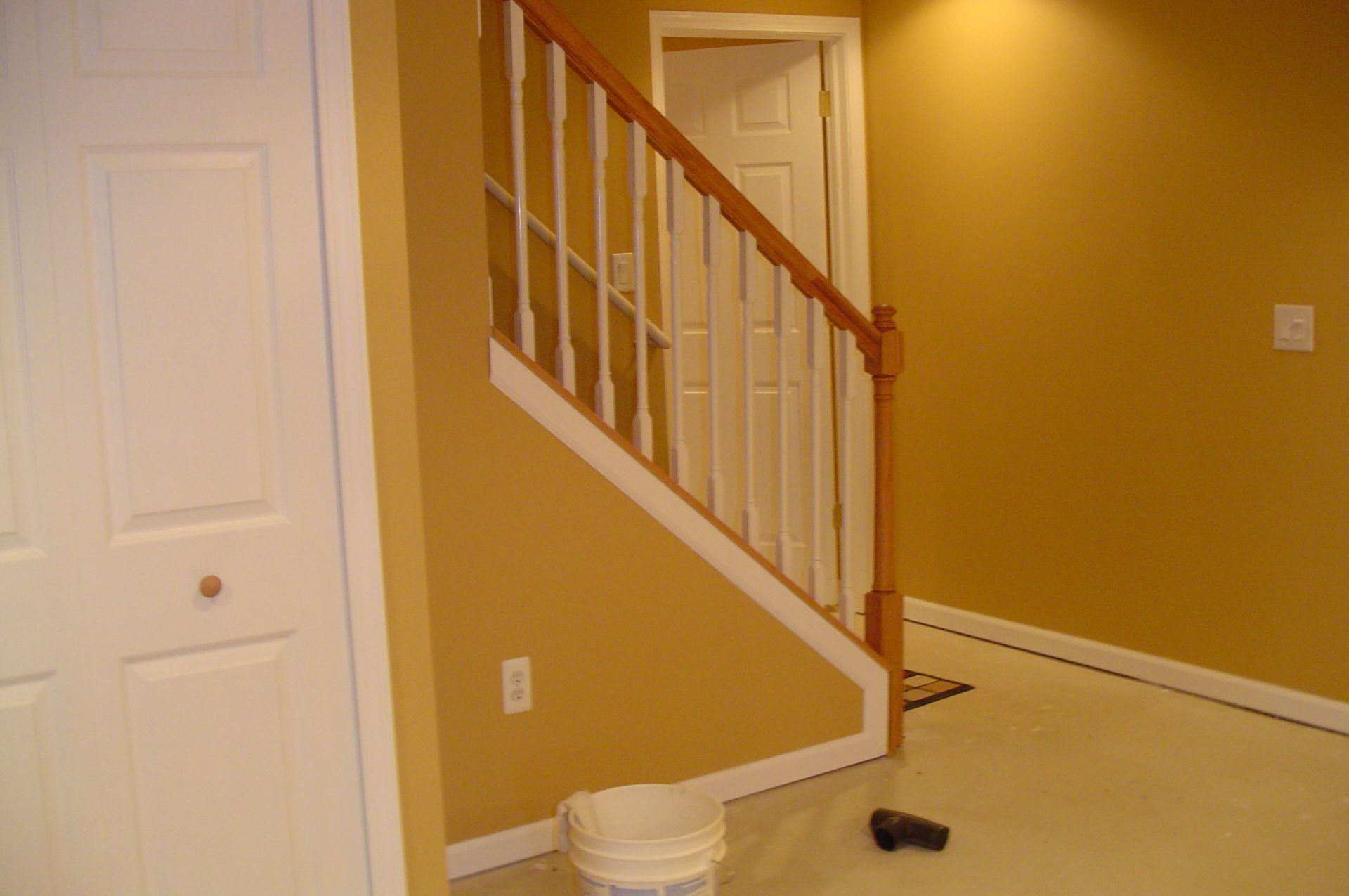 Interior with stairs, door, and closet. Yellow walls, white trim, and tan flooring.