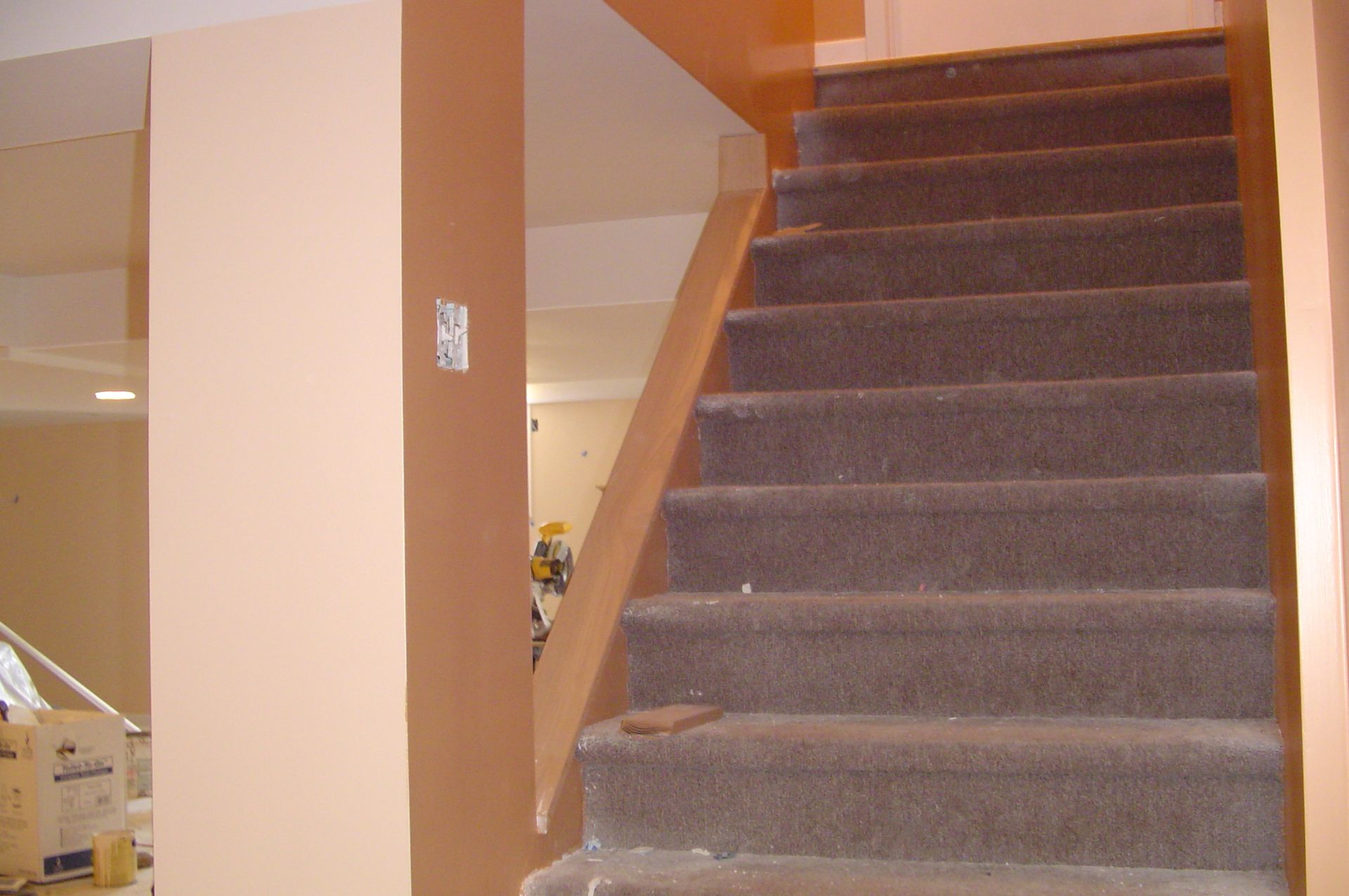 Staircase with brown carpet and peach-colored walls, leading upwards.