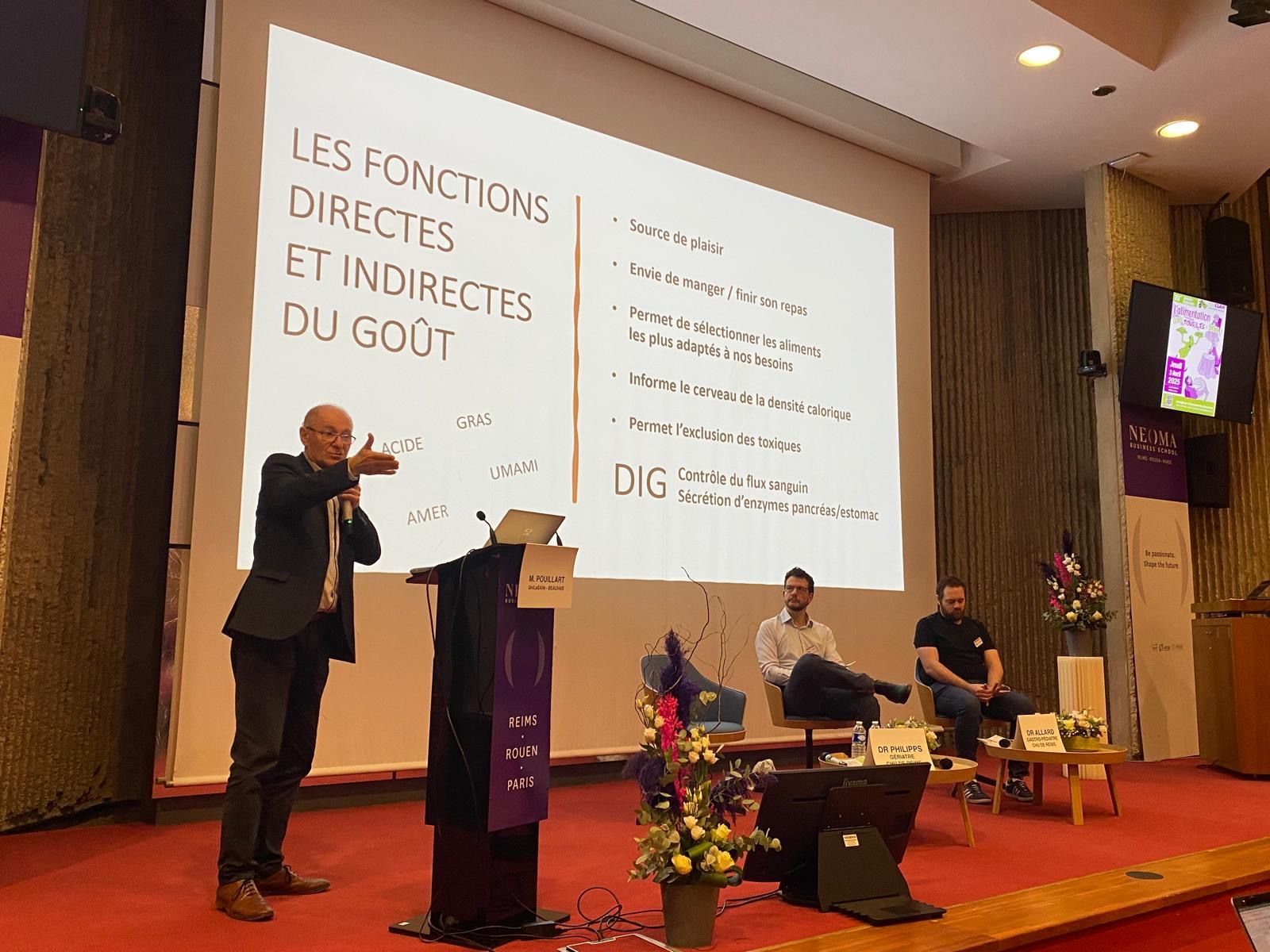 A speaker gestures toward a presentation titled 