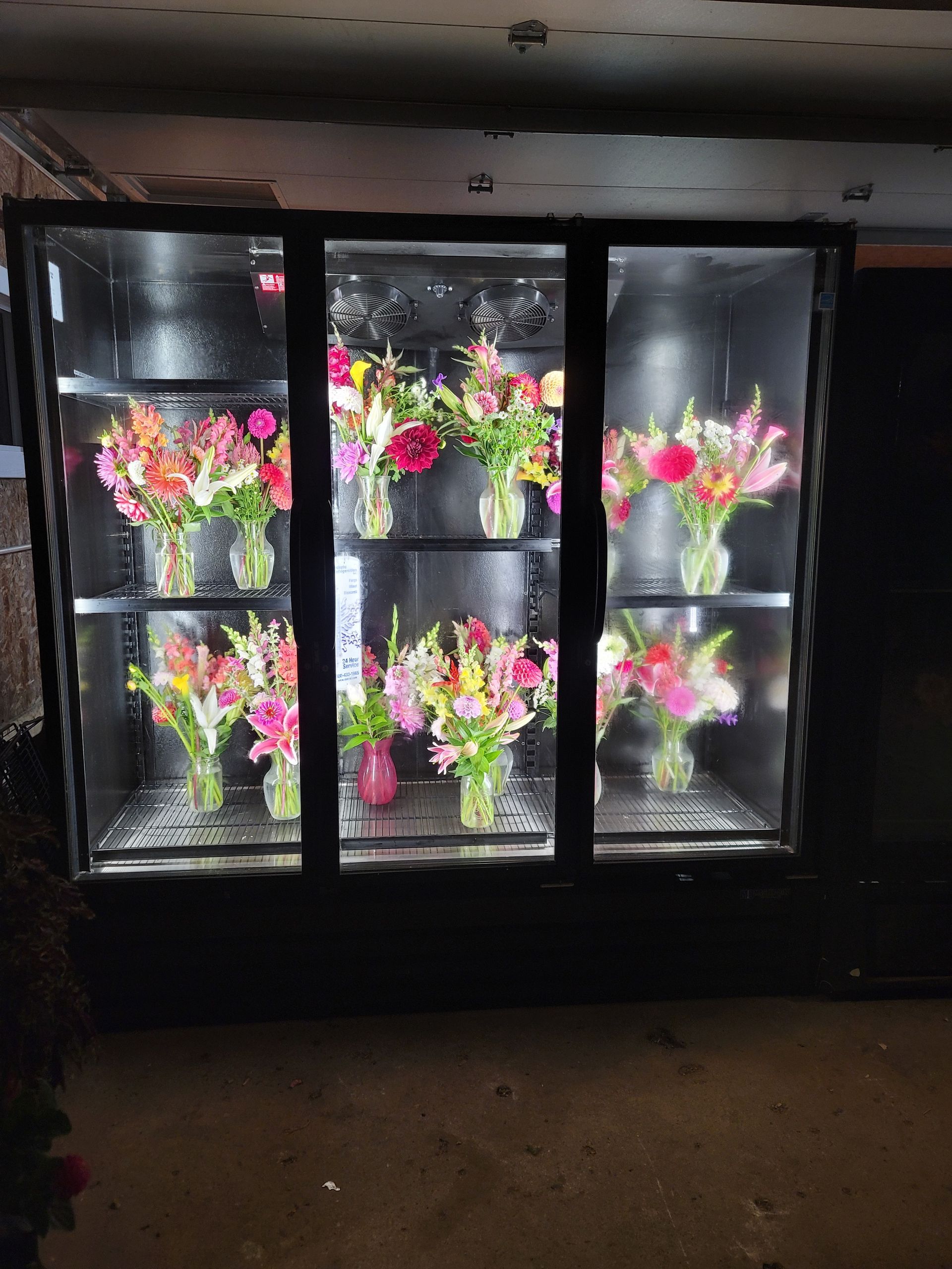 Flower display case with bright bouquets of pink and yellow flowers, set inside.