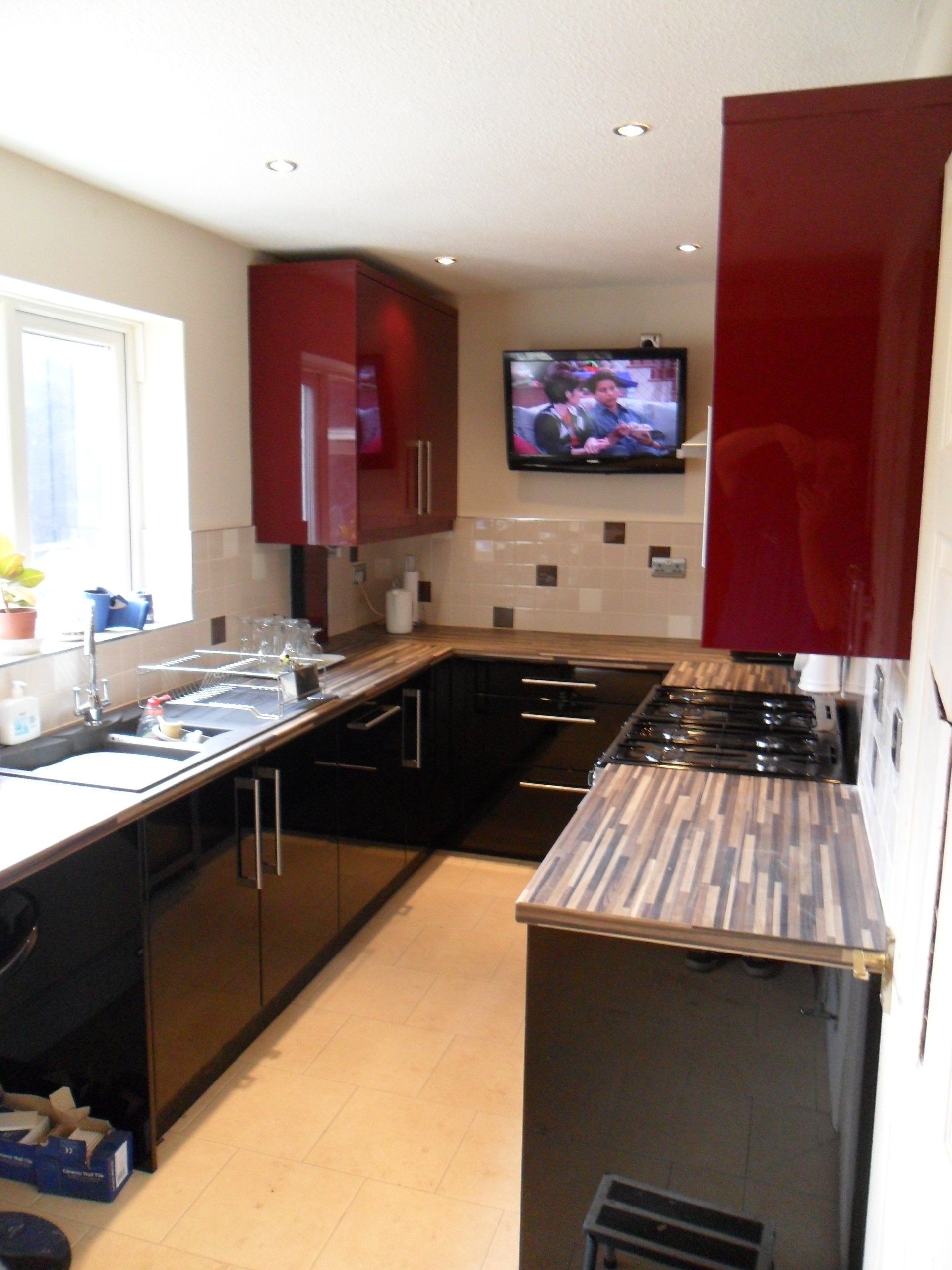 new kitchen cream wall tiles gloss burgundy red gloss black  cabinets Axiom worktop. wall tv