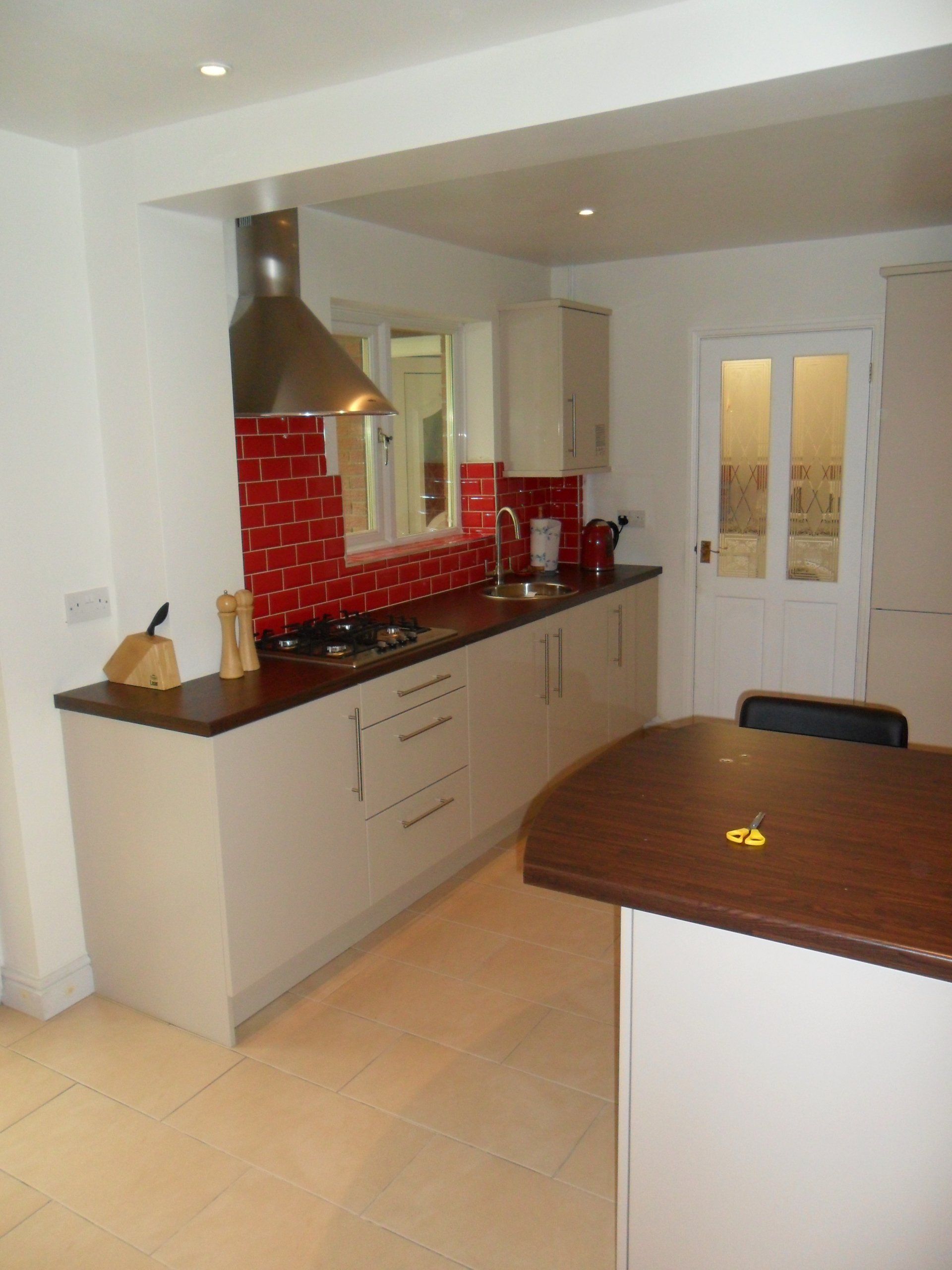 new kitchen bright red wall tiles gloss cream cabinets Axiom worktop cream floor tile