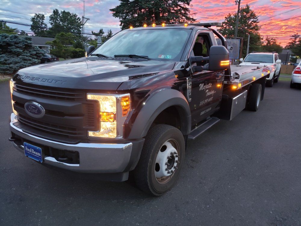 A black tow truck is parked on the side of the road.