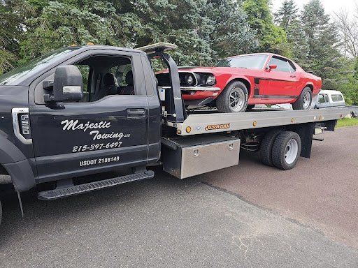 A red mustang is being towed by a tow truck.