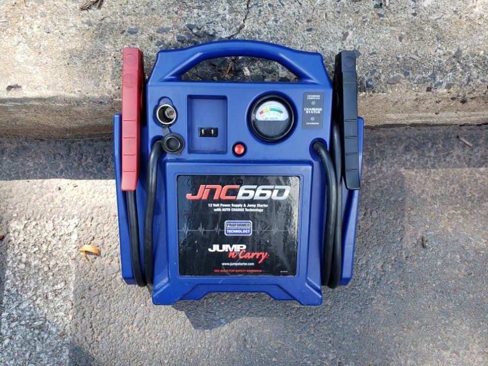 A blue jump starter is sitting on the ground