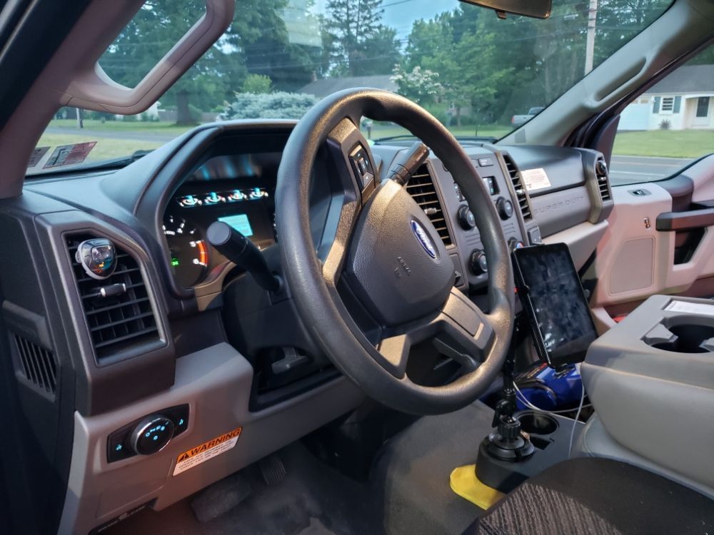 The inside of a ford truck with a phone mounted on the steering wheel