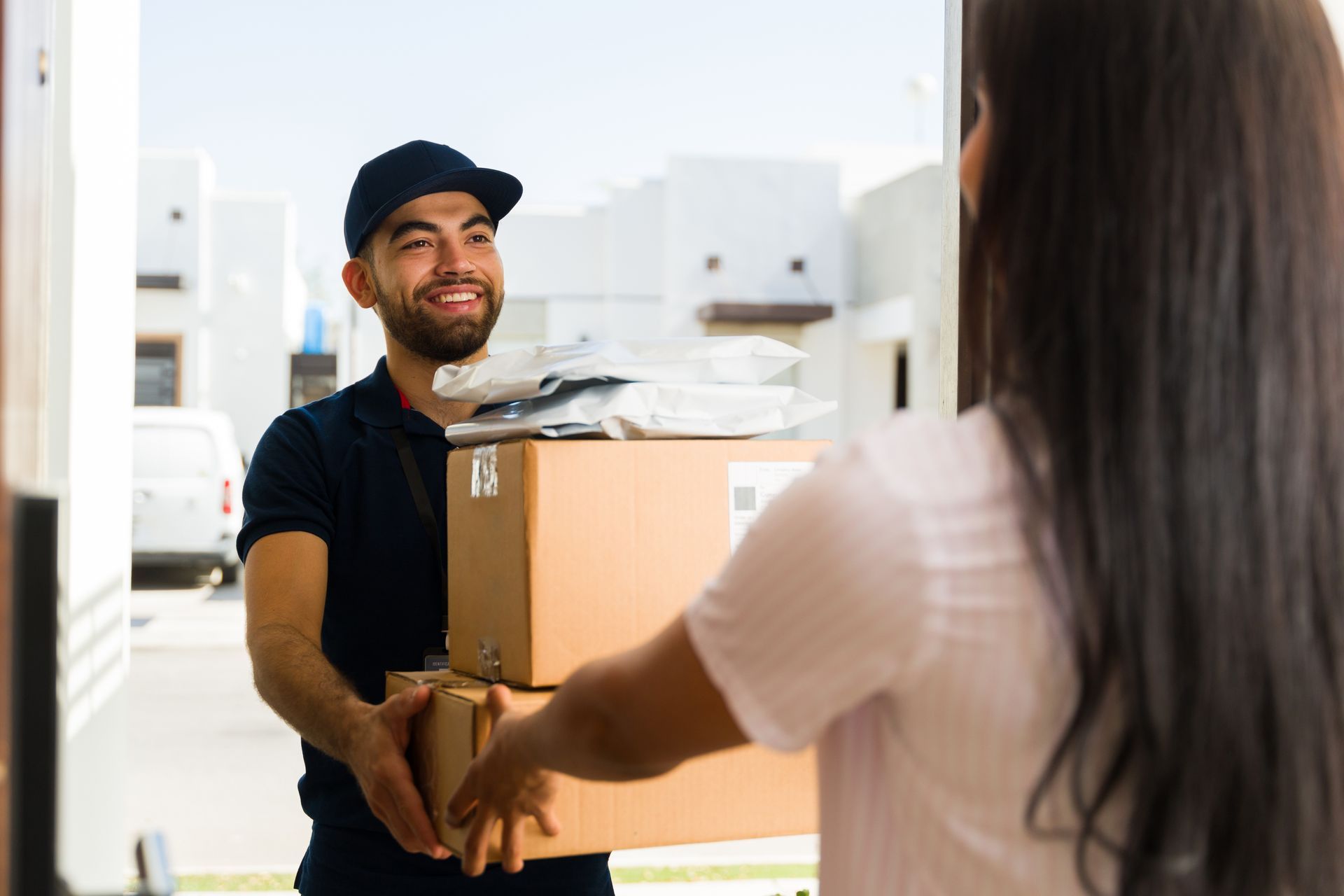 A delivery man is handing a box to a woman.