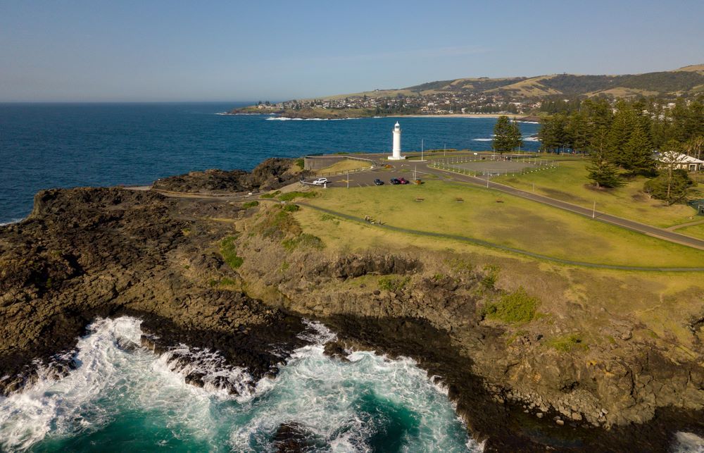 An Aerial View of a Lighthouse on a Cliff Overlooking the Ocean — Timms Roofing In Kiama, NSW
