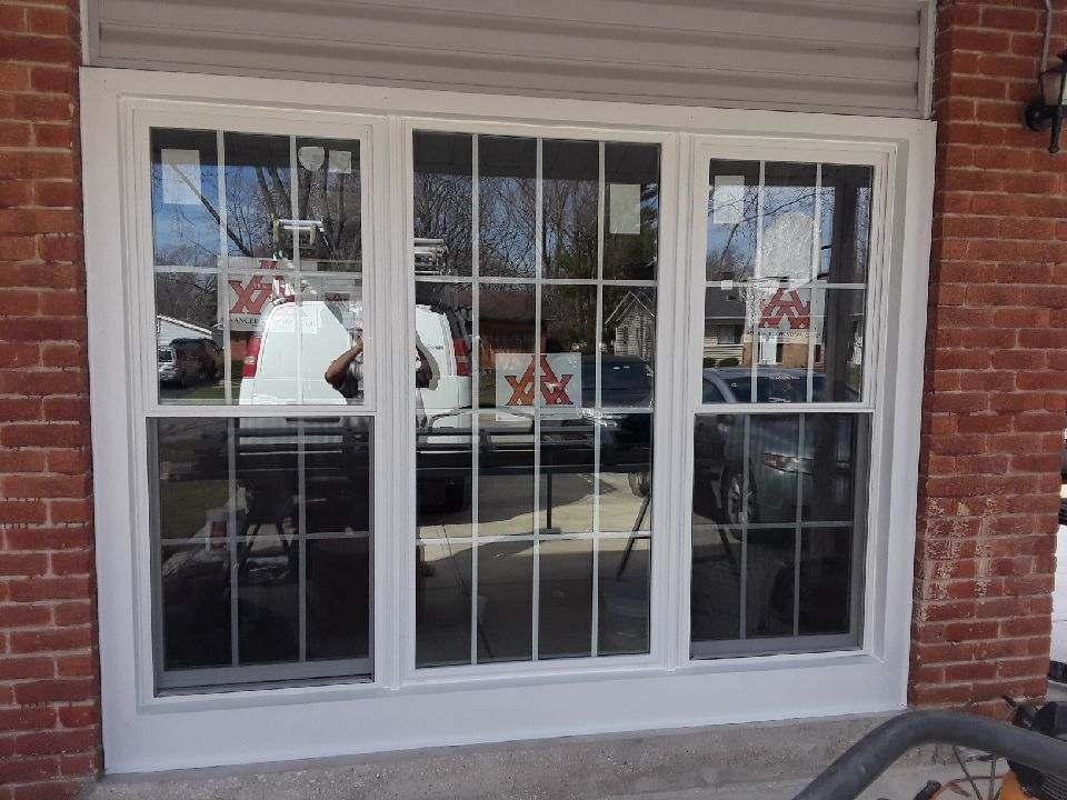 A large window on a brick building with a vacuum cleaner in front of it.