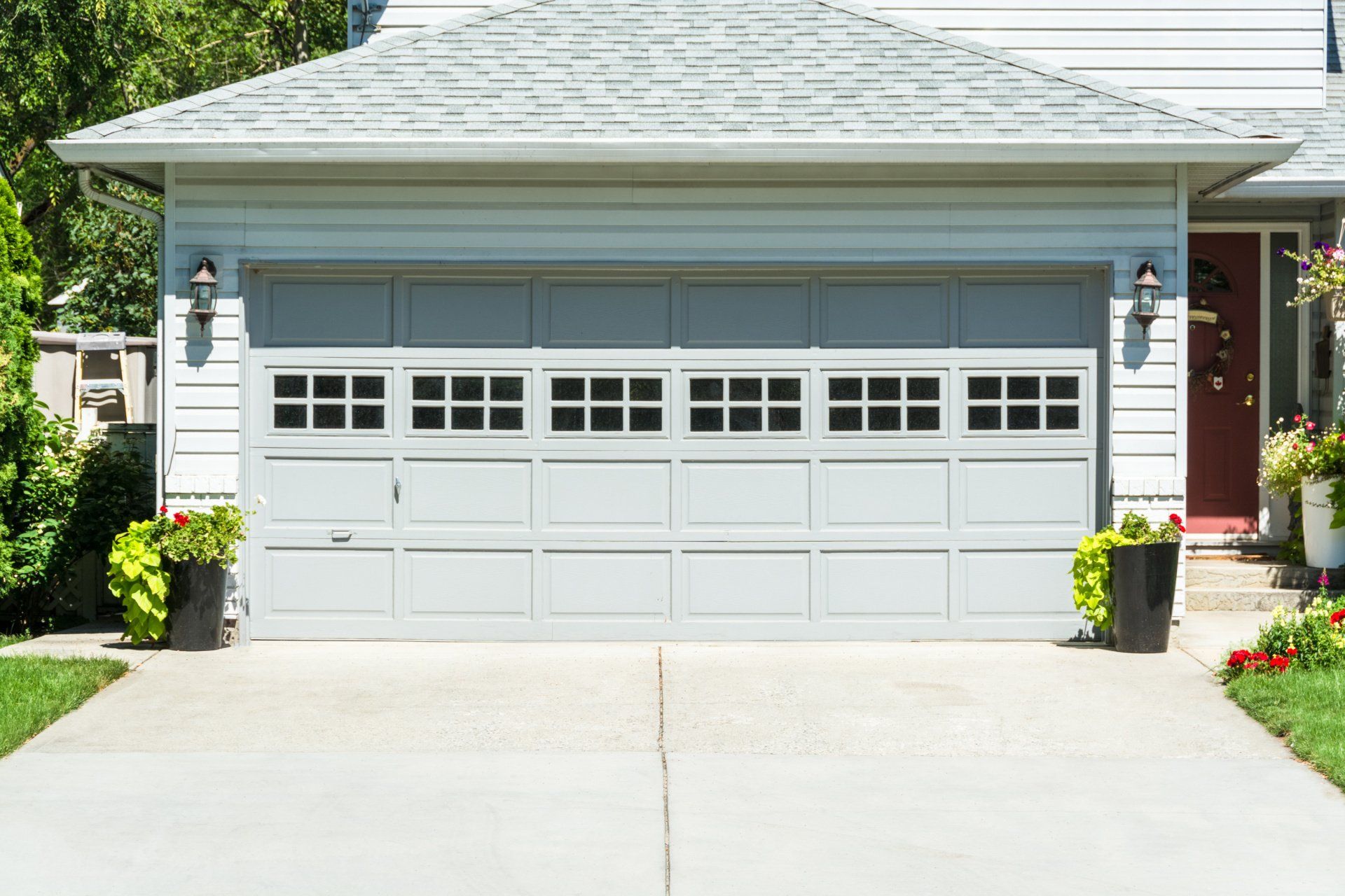 A white garage door is sitting in front of a white house.