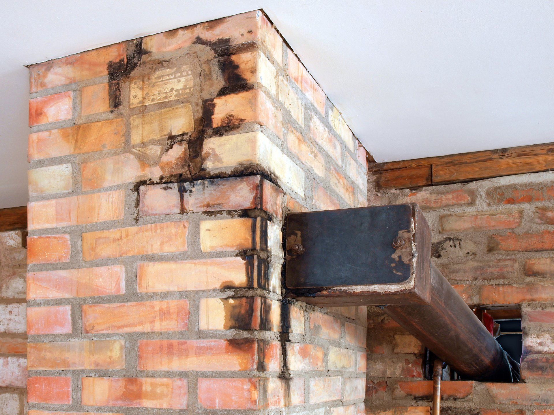 A brick chimney with a metal beam attached to it.