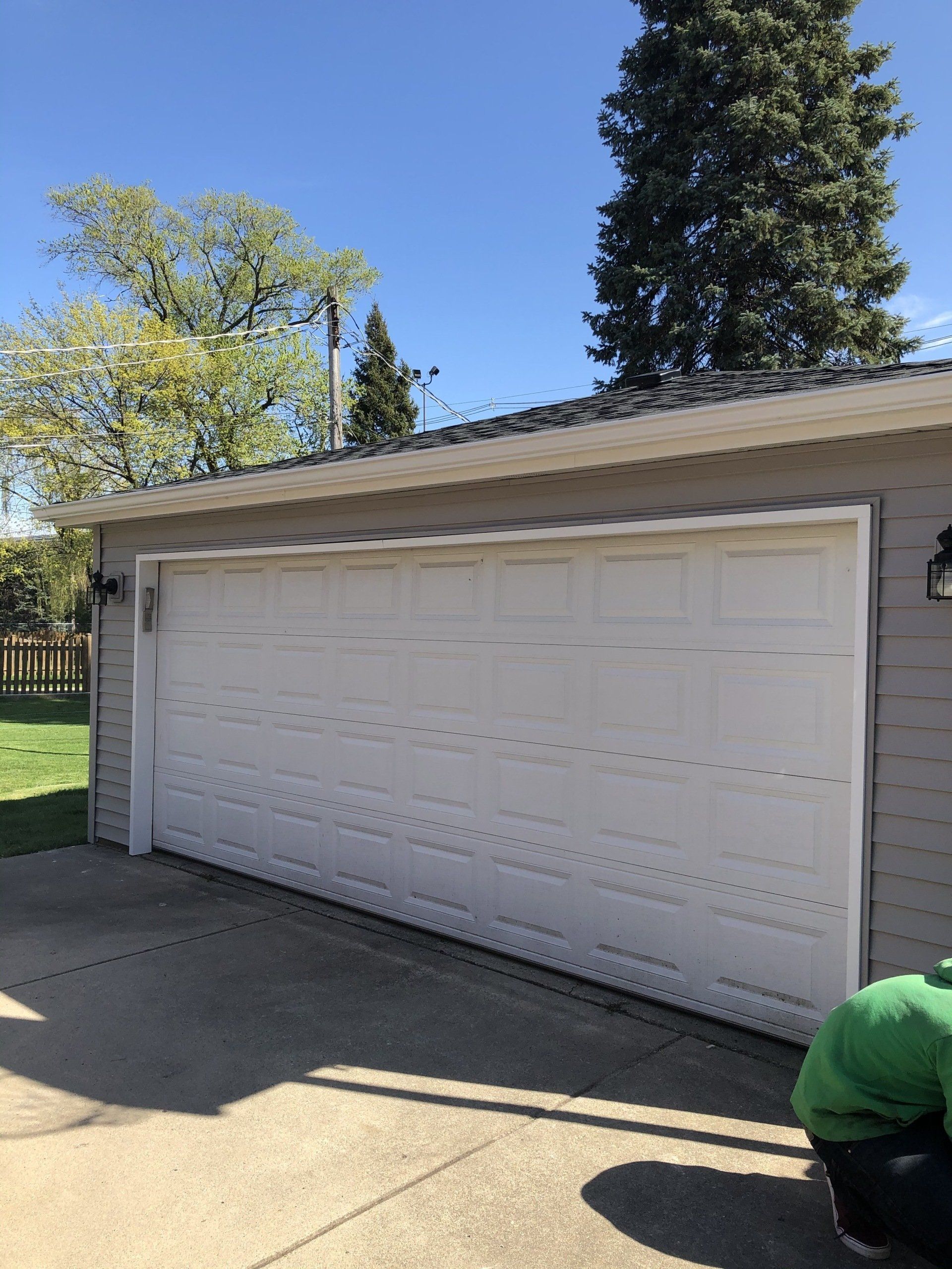 A man is kneeling in front of a white garage door.