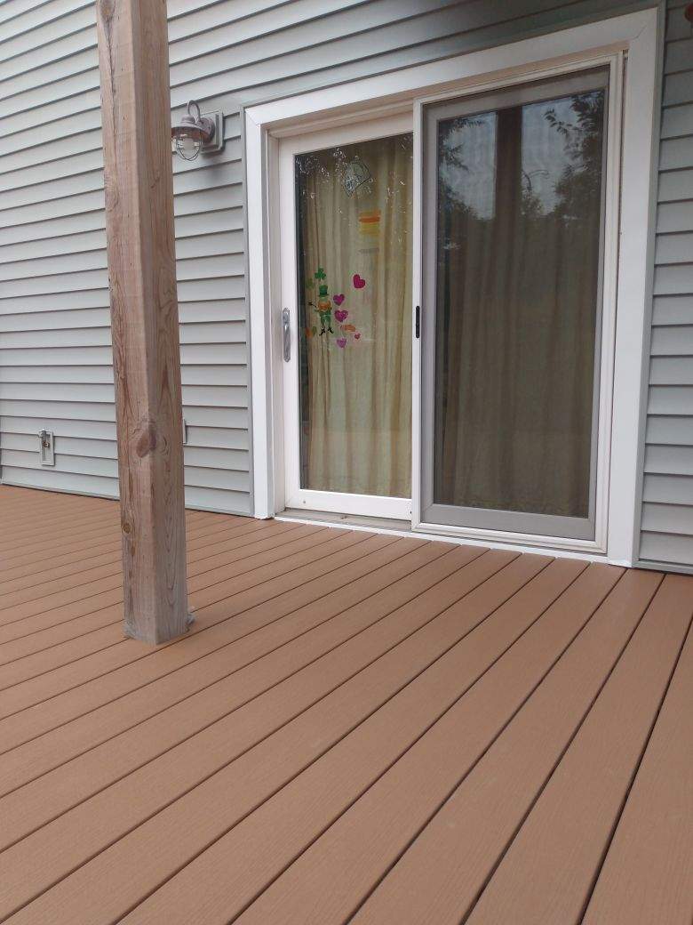 A deck with a sliding glass door in front of a house.