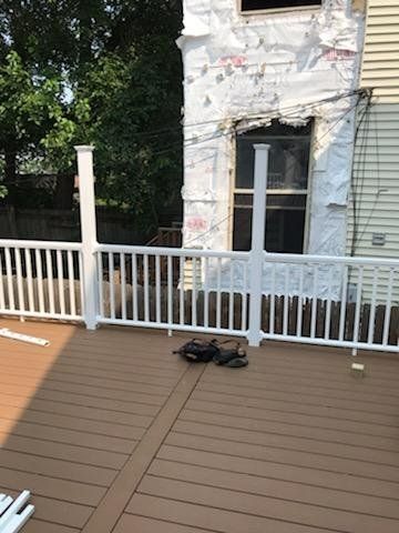 A deck with a white railing in front of a house.