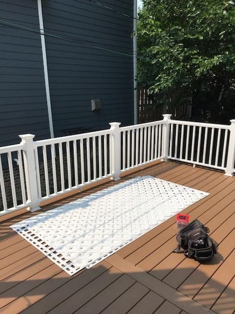 A deck with a white fence and a rug on it