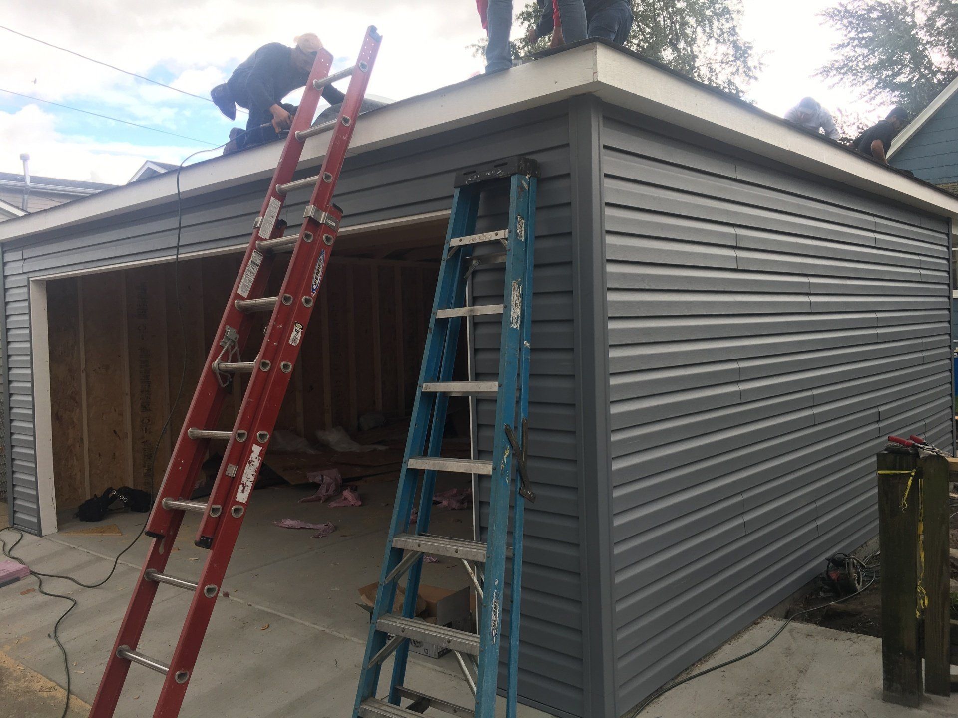 A man is working on the roof of a garage with a ladder.